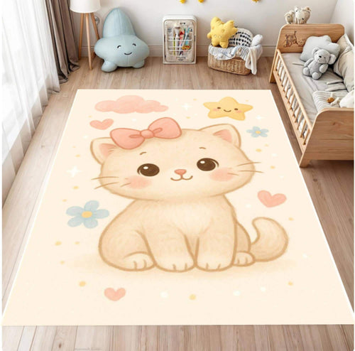 A large rectangular area rug with a cute cartoon kitten design, shown in a styled children's bedroom. The rug features a cream-colored kitten with a pink bow, surrounded by pastel pink clouds, blue flowers, and yellow stars on a warm cream background.