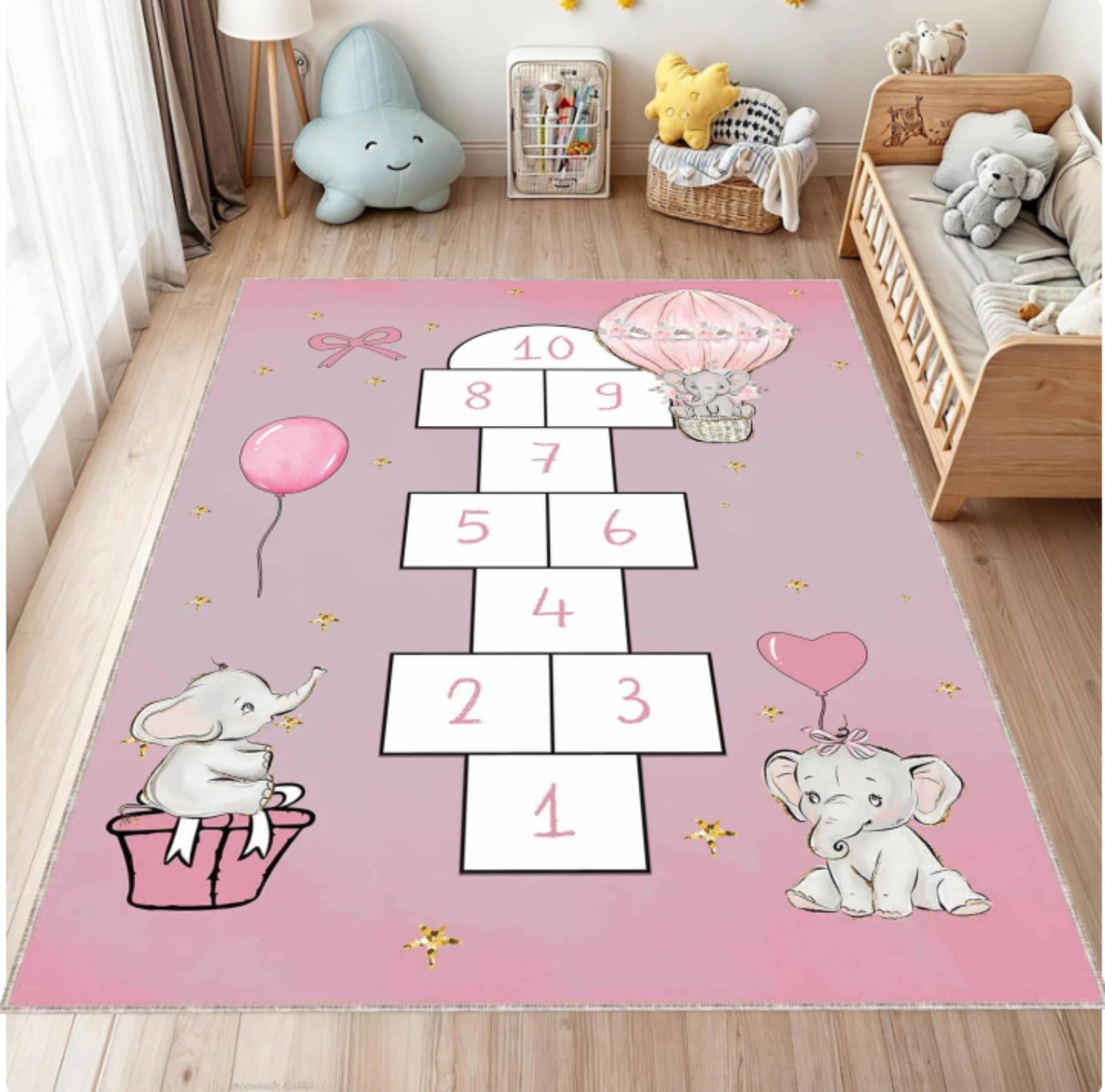 Pink children's rug with elephant and hopscotch design in a room with toys and furniture.