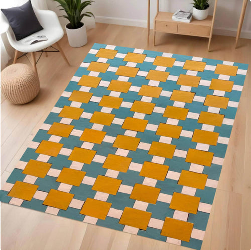 A rectangular area rug with a geometric interlocking block pattern in teal blue, mustard yellow, and light pink, shown on a light wood floor in a modern living room setting.