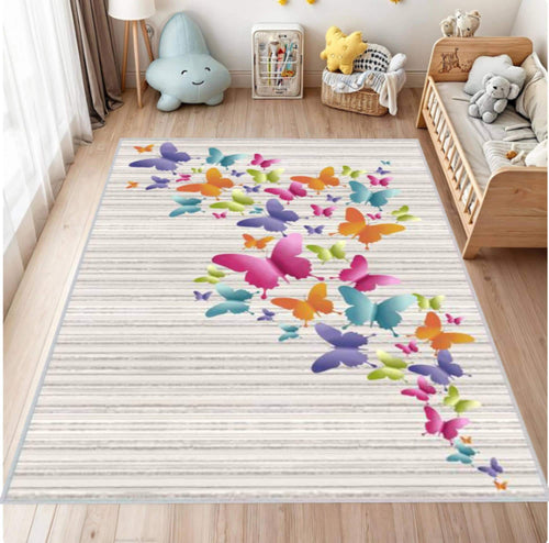 A rectangular area rug with a light beige wood-grain striped background and a vibrant, multicolored butterfly pattern flowing from the left edge toward the right, shown in a styled children's bedroom setting.