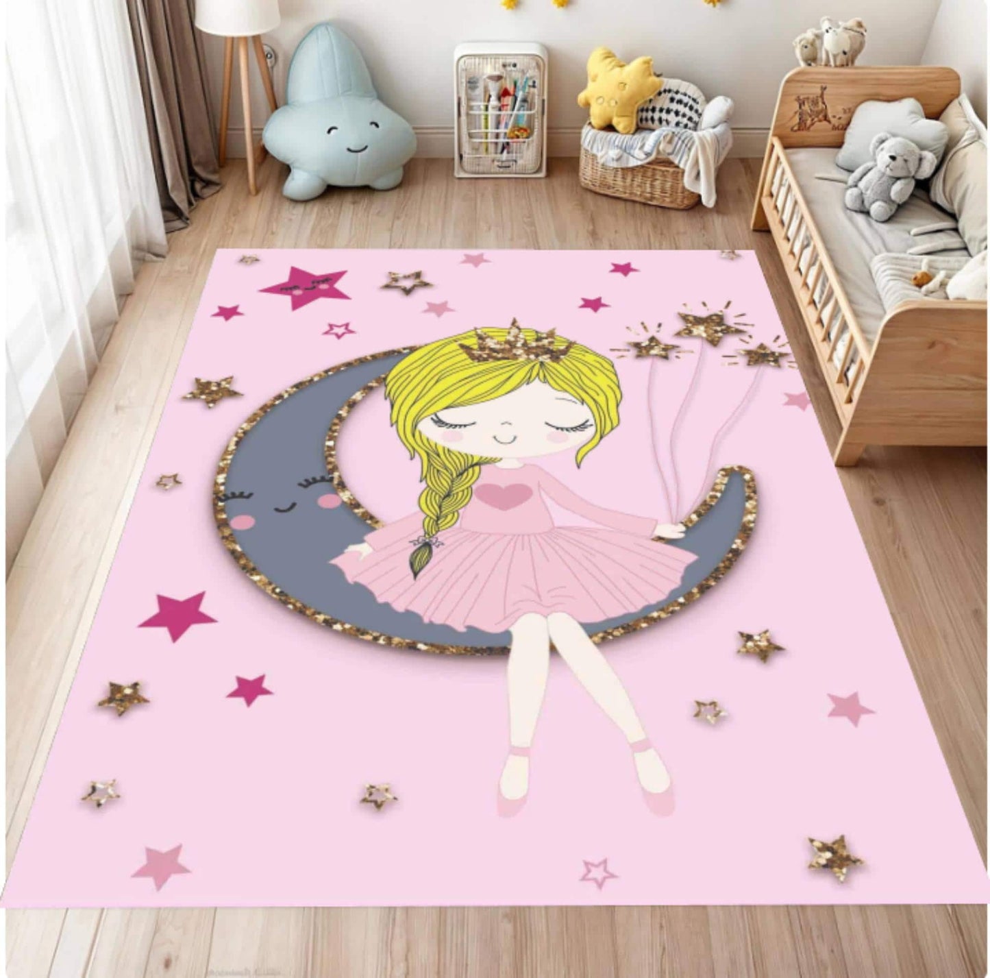 A pink children's area rug featuring a cartoon girl in a pink dress sitting on a gray crescent moon with gold star accents, shown in a styled bedroom setting.