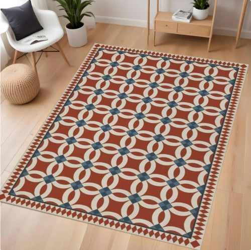 Patterned rug on a wooden floor with a chair, plant, and small table in the background.