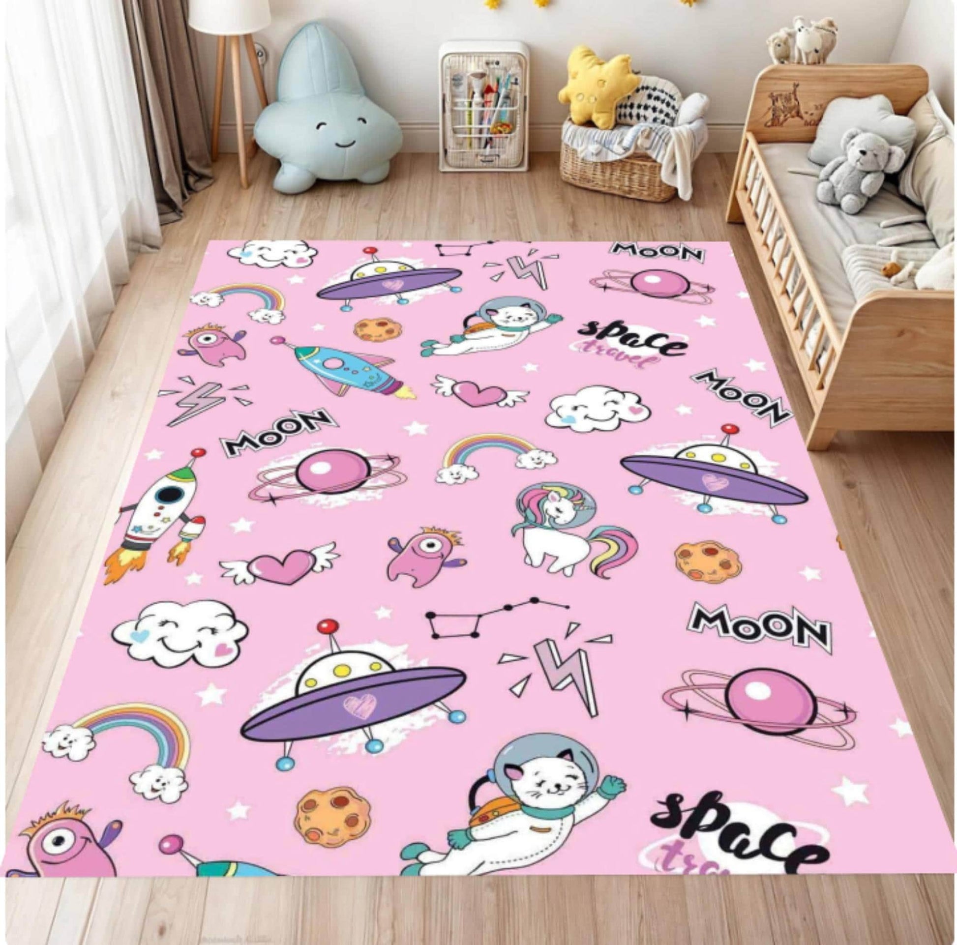 Pink children's rug with space-themed design in a room with toys and furniture.