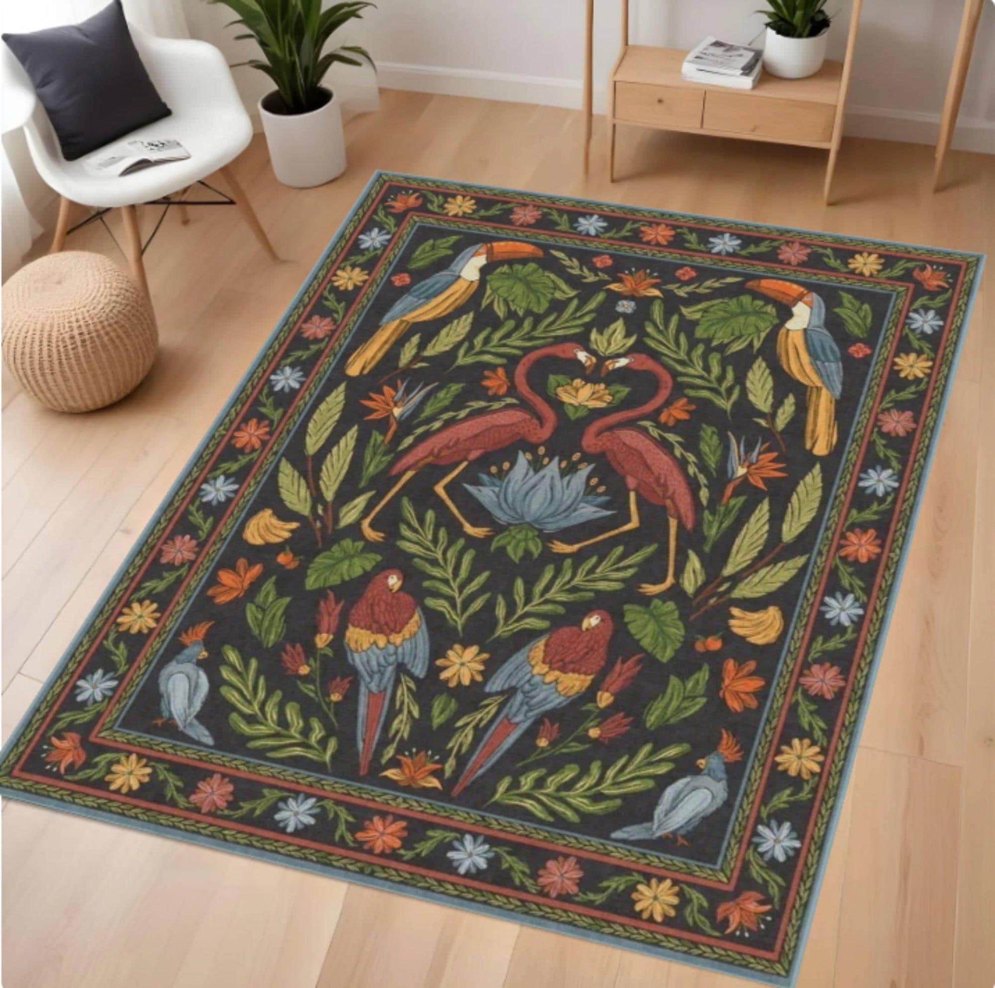 A rectangular area rug with a dark charcoal background and a colorful tropical design featuring red flamingos, toucans, parrots, and green foliage, styled on a light wood floor in a modern living room setting.