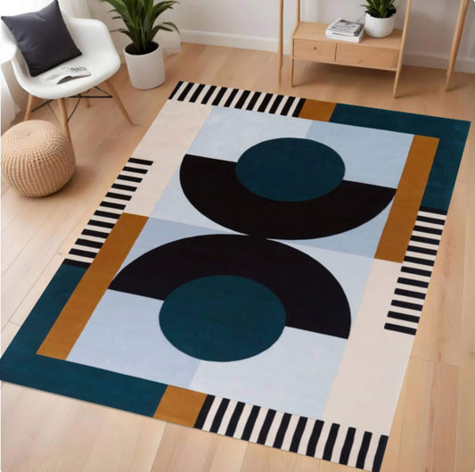 A modern geometric area rug with abstract shapes in teal, black, navy, light blue, cream, and mustard, shown in a bright living room setting.