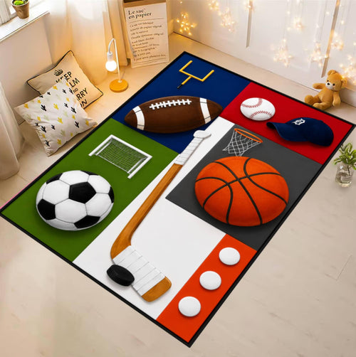 A rectangular sports-themed area rug laid out on a light wood floor in a styled room. The rug features large sections and illustrations of different sports balls and equipment, including a soccer ball, football, basketball, baseball, hockey stick, hockey puck, goals, and a net, arranged on a white background with black dividing lines.