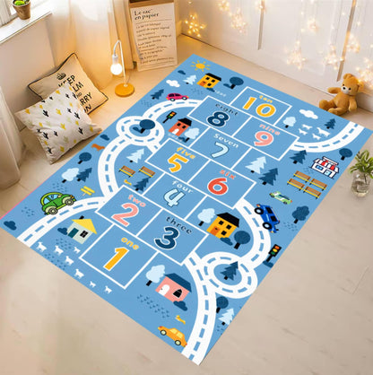 A children's play mat with a road-style hopscotch layout in light blue, shown on a light wood floor in a styled room with pillows, a lamp, string lights, and a teddy bear.