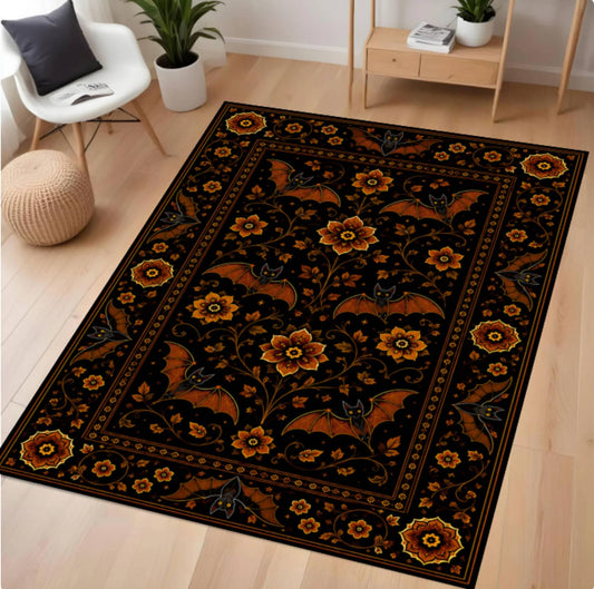 A rectangular area rug with a black background and an ornate floral and bat pattern in orange, gold, and dark blue, shown on a light wood floor in a styled room.