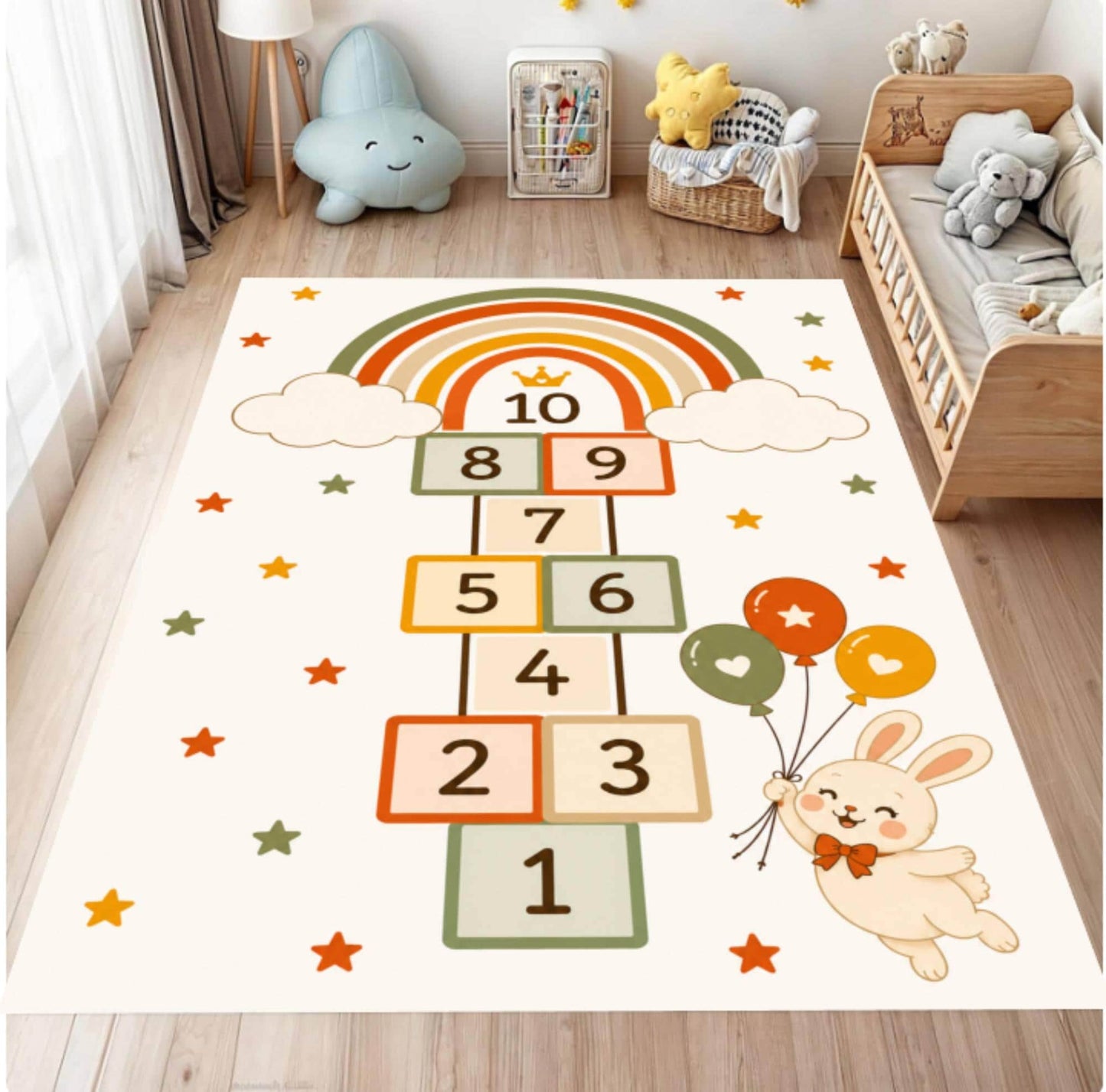 A rectangular children's play rug featuring a hopscotch grid with numbers 1 through 10, a rainbow, clouds, stars, and a cartoon bunny holding balloons, shown on a wooden floor in a styled nursery.